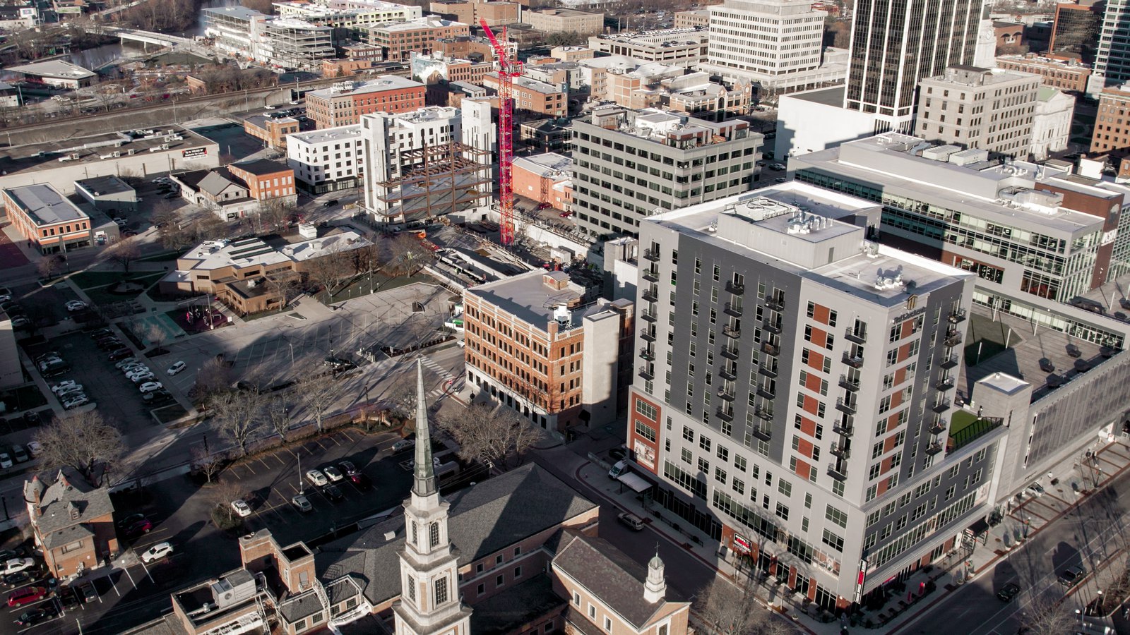 Downtown blocks with a church spire and a construction crane, from the drone