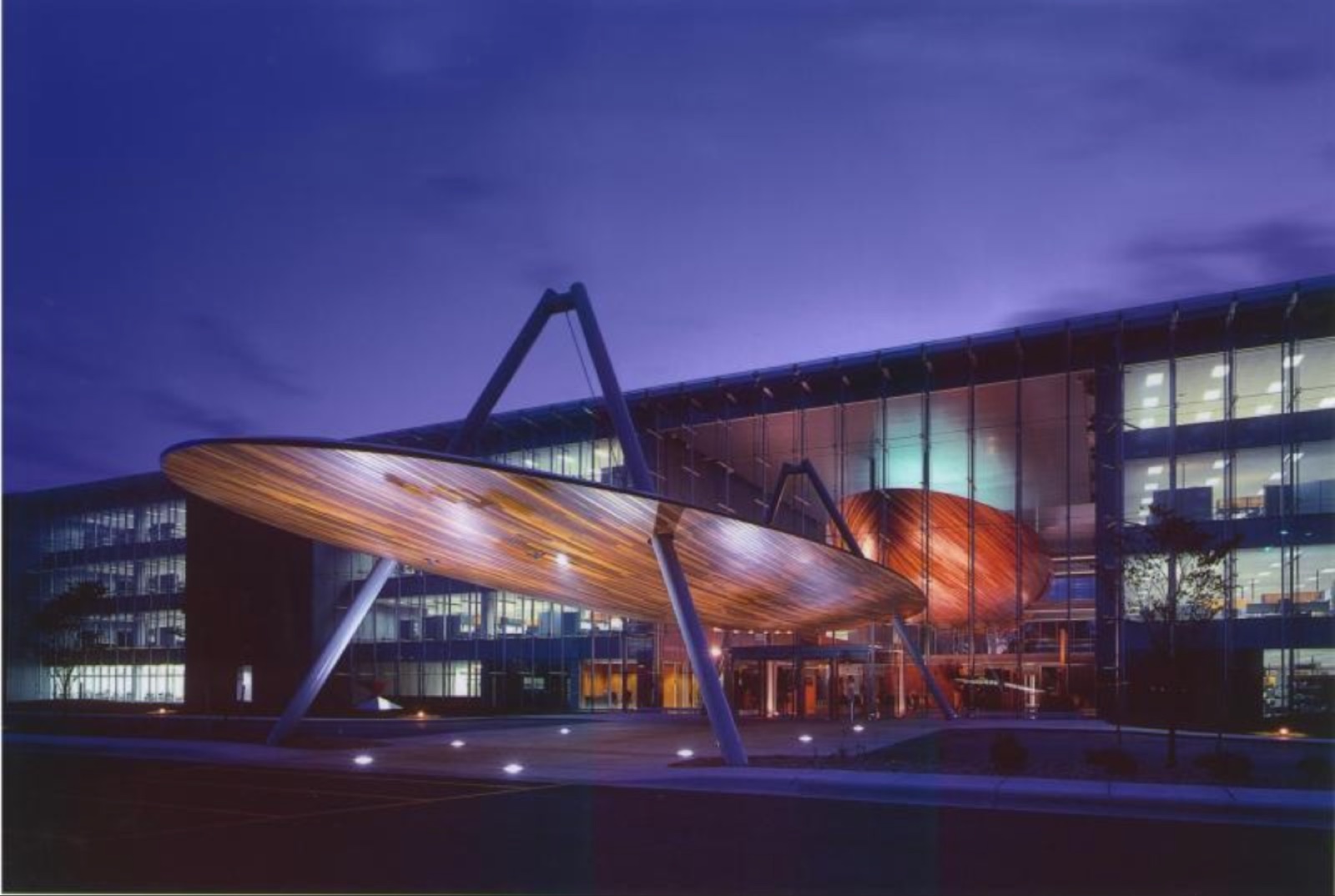 Glass office building with a wooden canopy at dusk