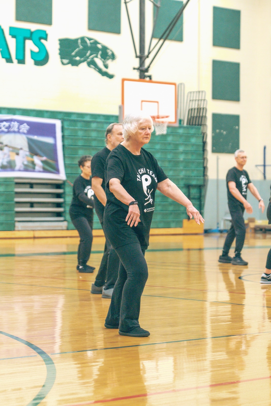 Tai chi class practicing in a gym