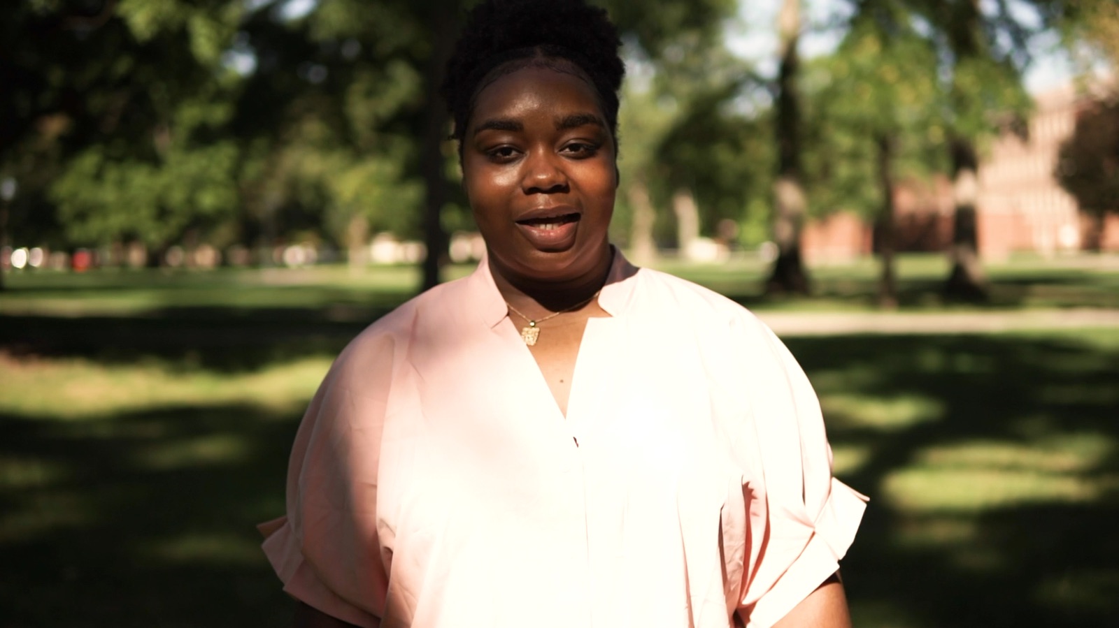 Woman speaking on a sunny campus lawn