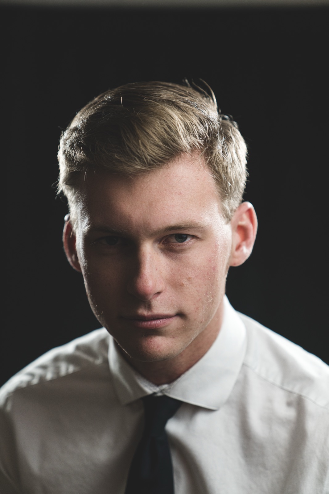Studio headshot of a young man in a white shirt