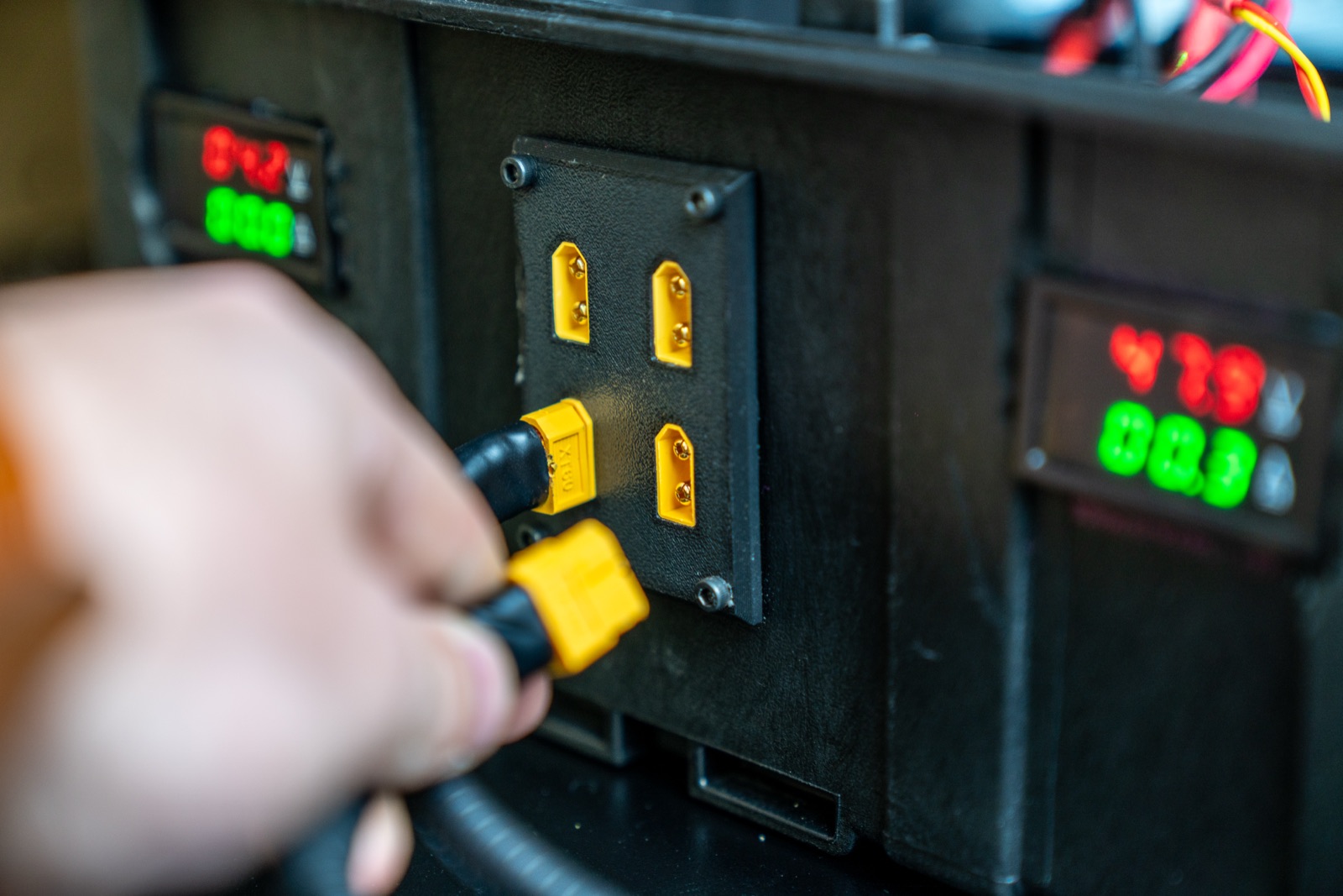 Hand connecting a cable at a test station with digital readouts