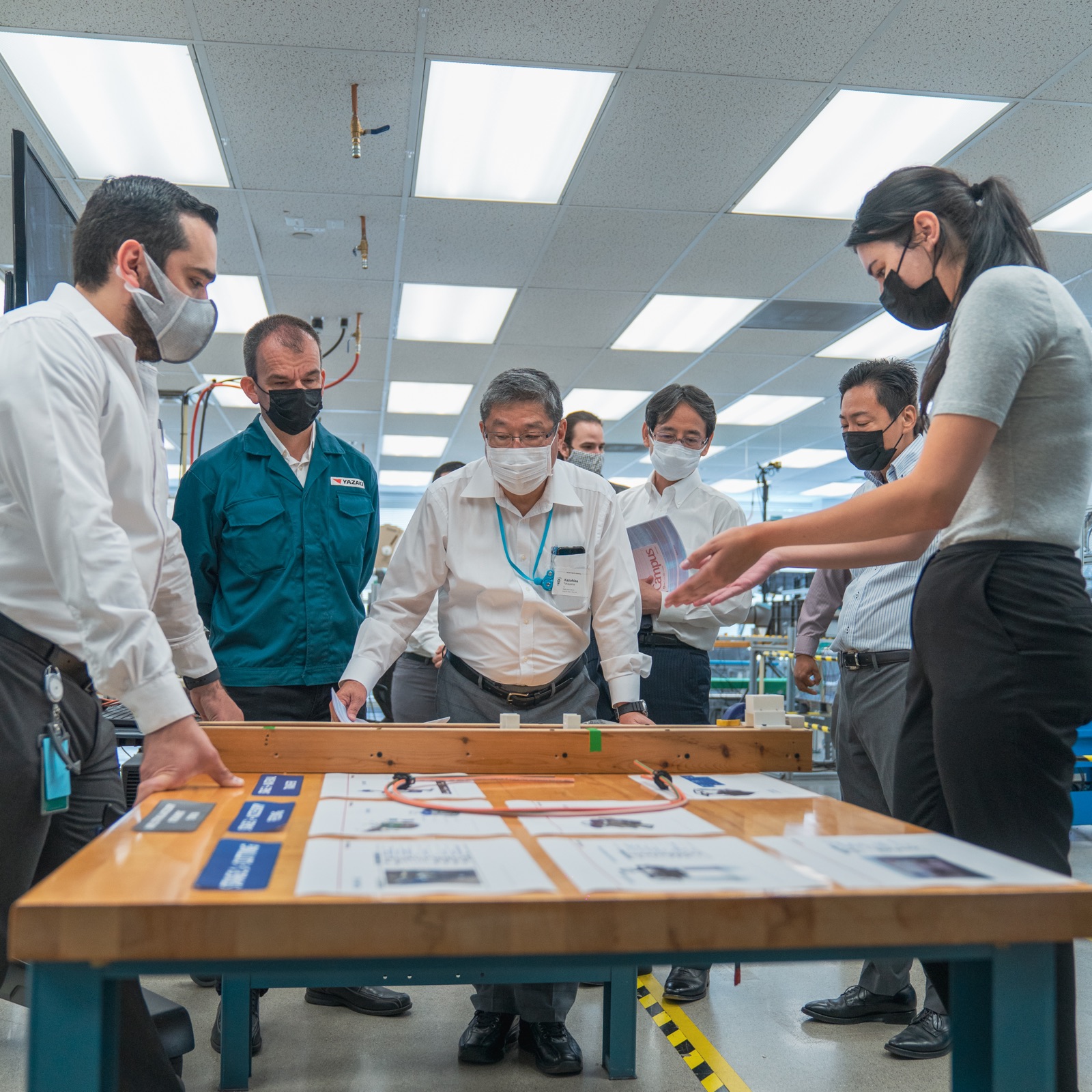 Group gathered around a training table in a factory dojo